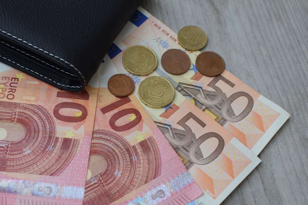 Black,Wallet,With,Euro,Currency,Banknotes,And,Coins,On,Natural