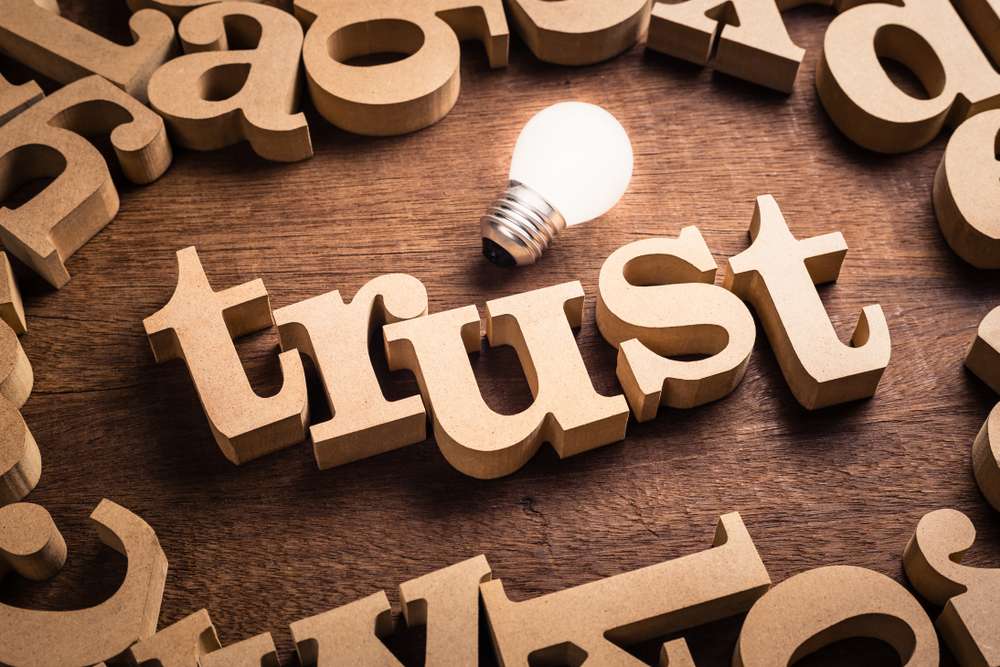 Trust,Word,In,Scattered,Wood,Letters,With,Glowing,White,Light