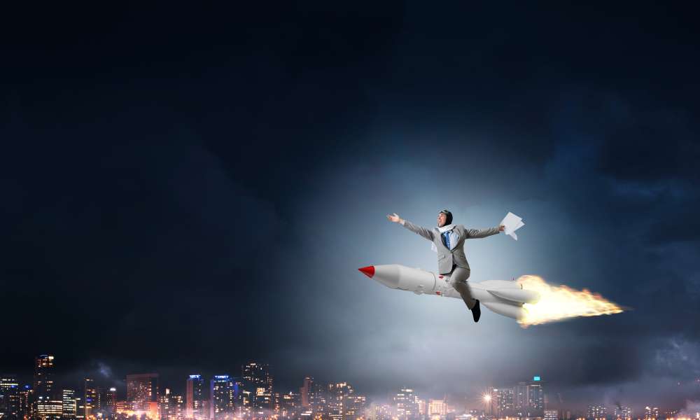 Conceptual,Image,Of,Young,Businessman,In,Suit,Flying,On,Rocket